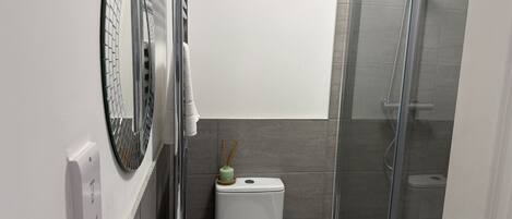 Um banheiro moderno com box de vidro, vaso sanitário branco e banheira.