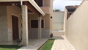 A courtyard with a paved walkway, a small grassy area, and a building with a tiled exterior.