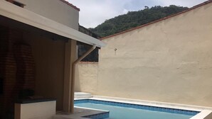 A swimming pool with steps leading up to it, surrounded by a tiled patio area.