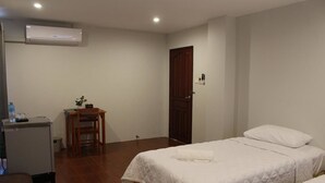 A hotel room with two beds, a desk with a chair, a small table with a plant, and an air conditioning unit on the wall. - Avalon residence2 (Savannakhet)