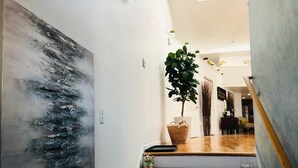 Modernilla designilla varustetut portaat johtavat oleskelutilaan, jossa on suuri kasvi ja kori.