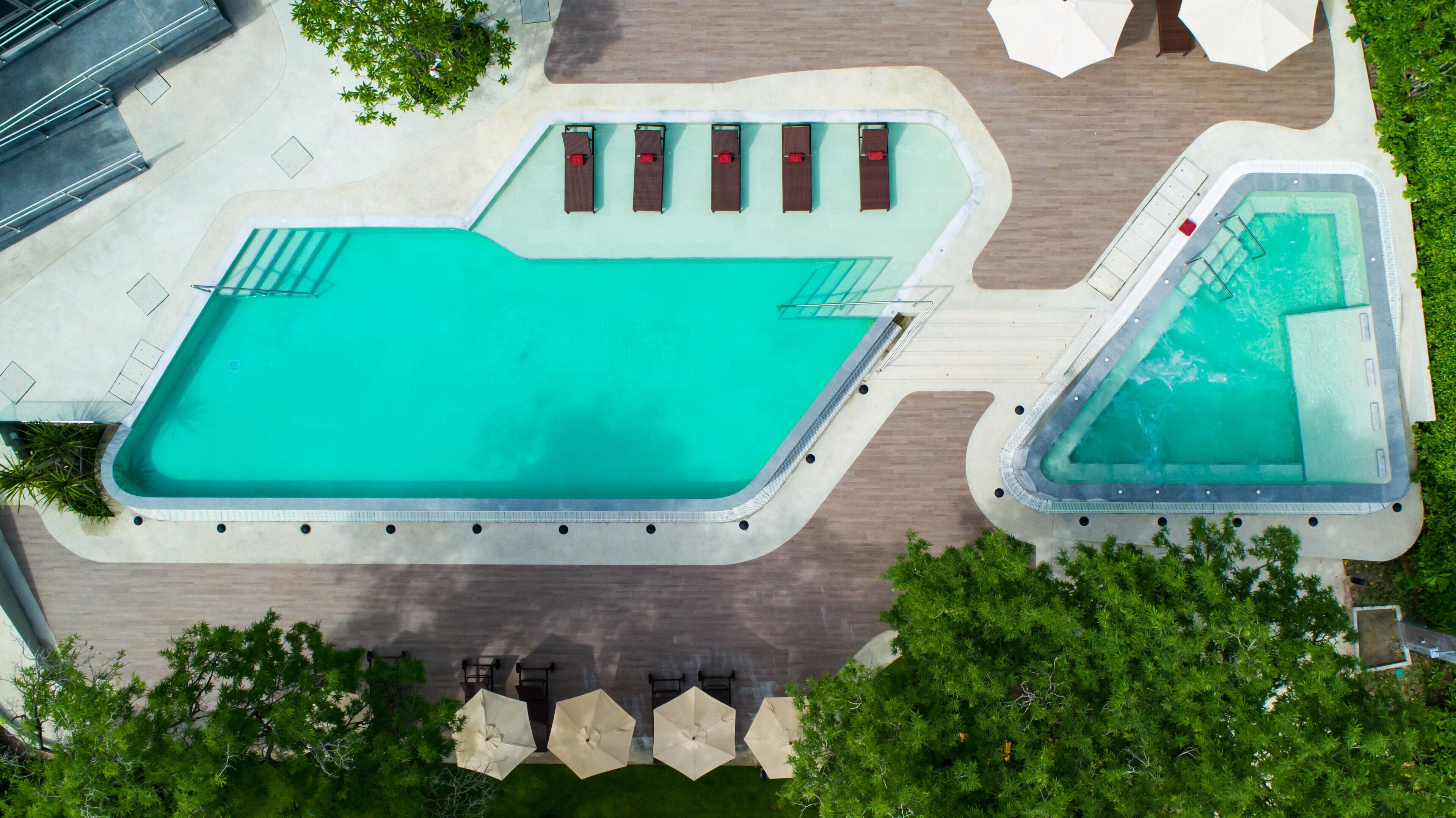 An aerial view of a swimming pool area with multiple pools and lounge chairs.