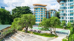 Un hotel moderno con zona de piscina, varios balcones y abundante vegetación.