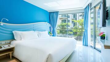 Habitación de hotel moderna con una cama grande, una mesita de noche, una ventana con cortinas y vistas a la ciudad.