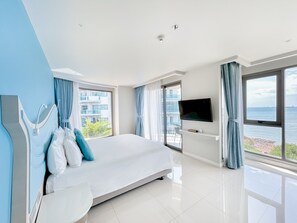 Une chambre d’hôtel moderne dotée d’un grand lit, d’une télévision à écran plat et d’un balcon offrant une vue sur la mer.