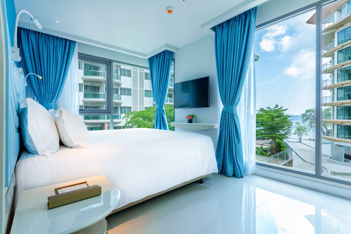 Ett modernt hotellrum med en stor säng, en platt-TV och en balkong med utsikt över staden.