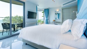 Un dormitorio moderno con una cama grande, un balcón con mesa y sillas, un televisor montado en la pared y vistas al exterior.