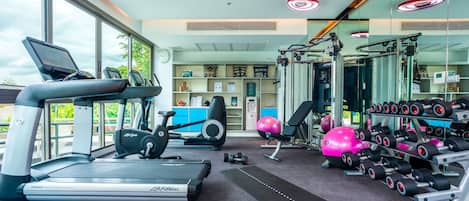 Un gimnasio con cintas de correr, elípticas, pesas libres y pelotas de ejercicio.