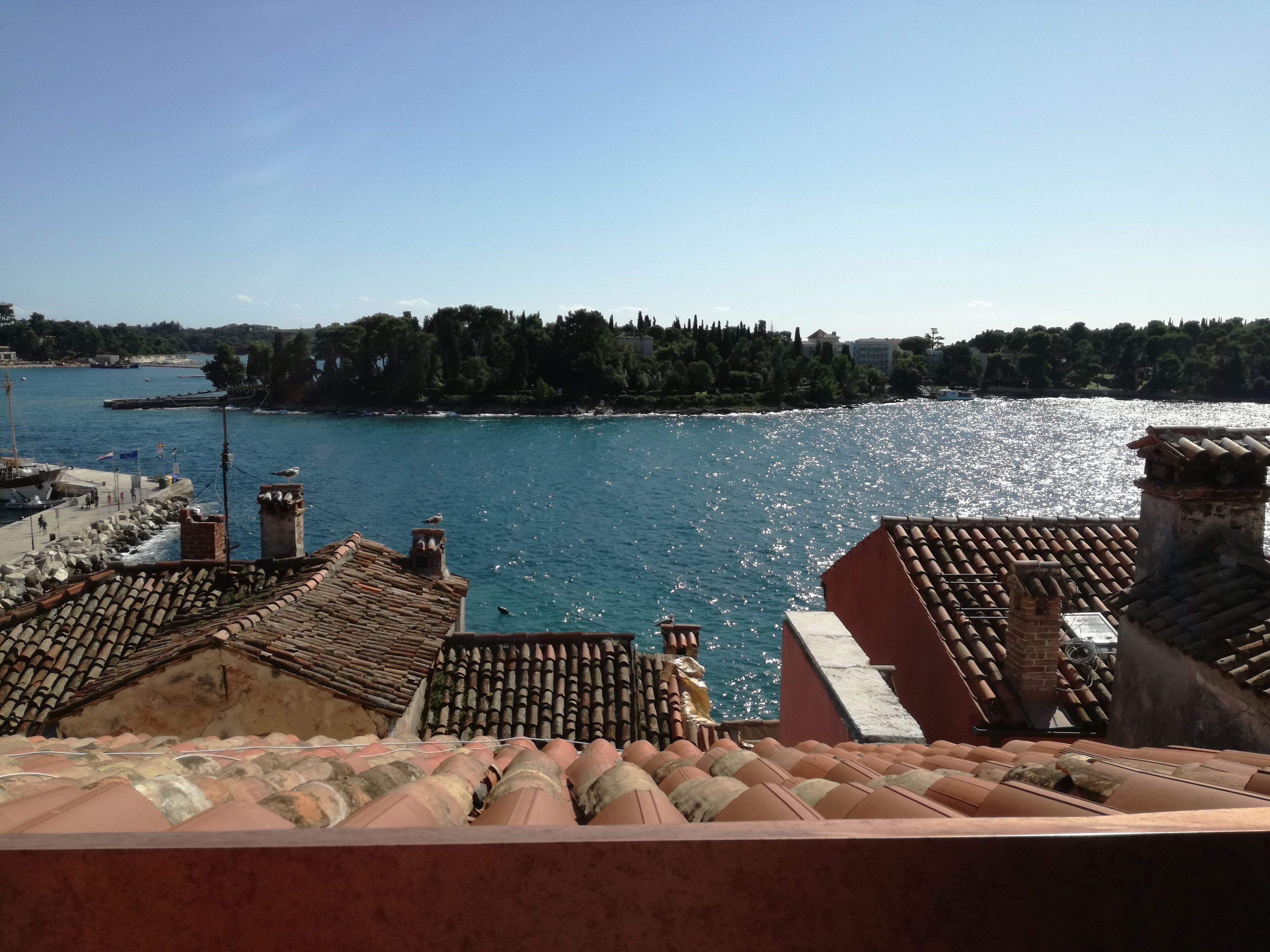 A coastal view with terracotta rooftops and a clear blue sea.