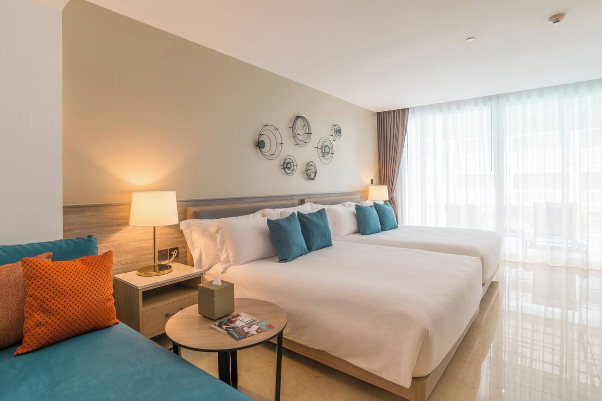 Ein Hotelzimmer mit zwei Betten, einem Nachttisch, einem runden Tisch und einem Wandbild.