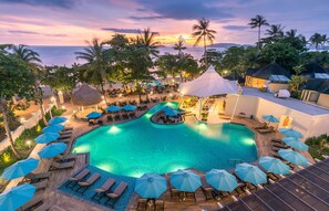 A resort pool area with lounge chairs and umbrellas, surrounded by palm trees and a view of the ocean. - Centara Ao Nang Beach Resort & Spa Krabi (Krabi)