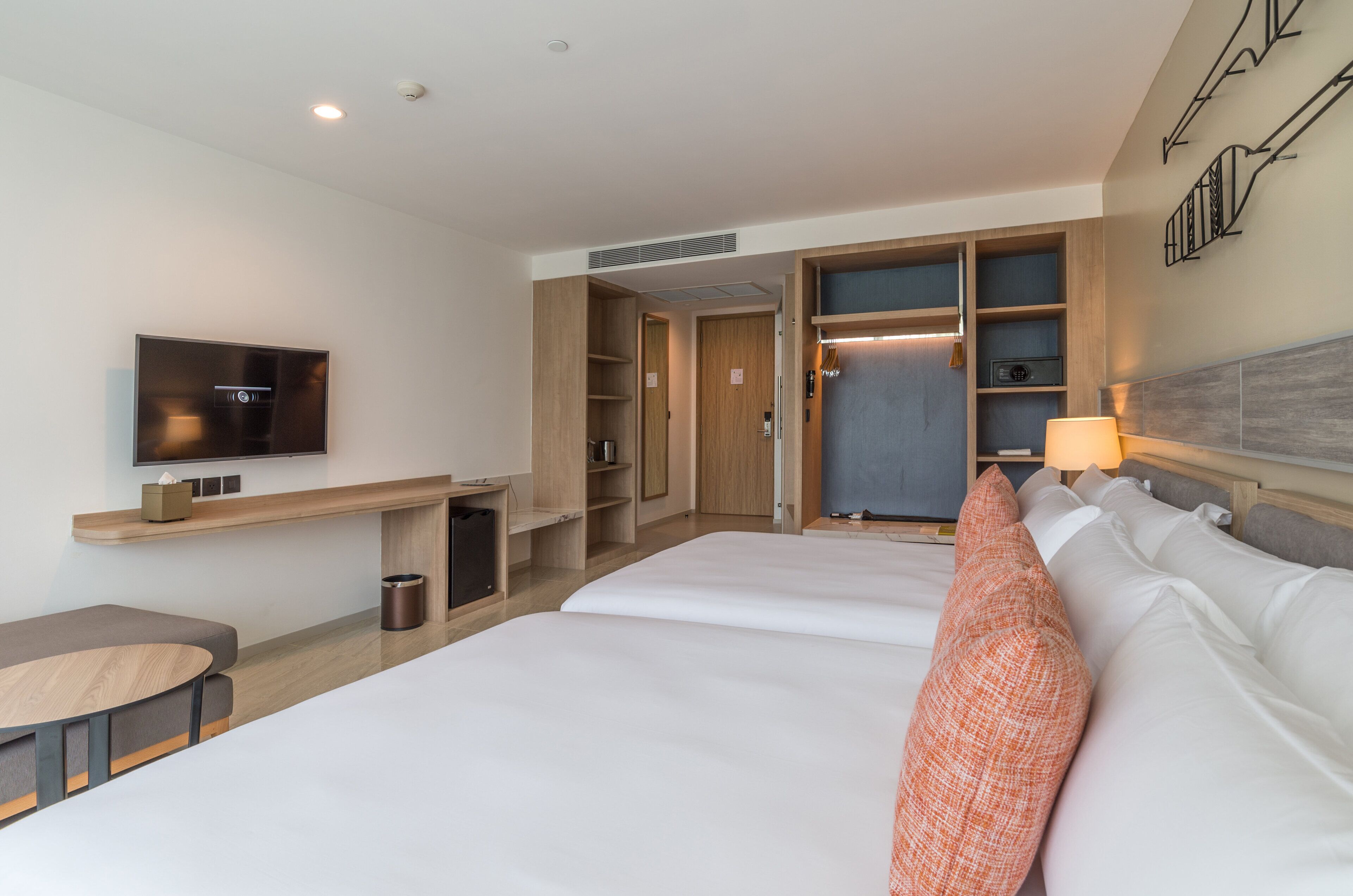 Una habitación de hotel con una cama, televisión, escritorio y armario.