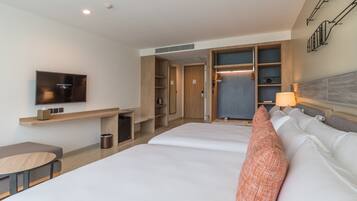 Una habitación de hotel con una cama, televisión, escritorio y armario.