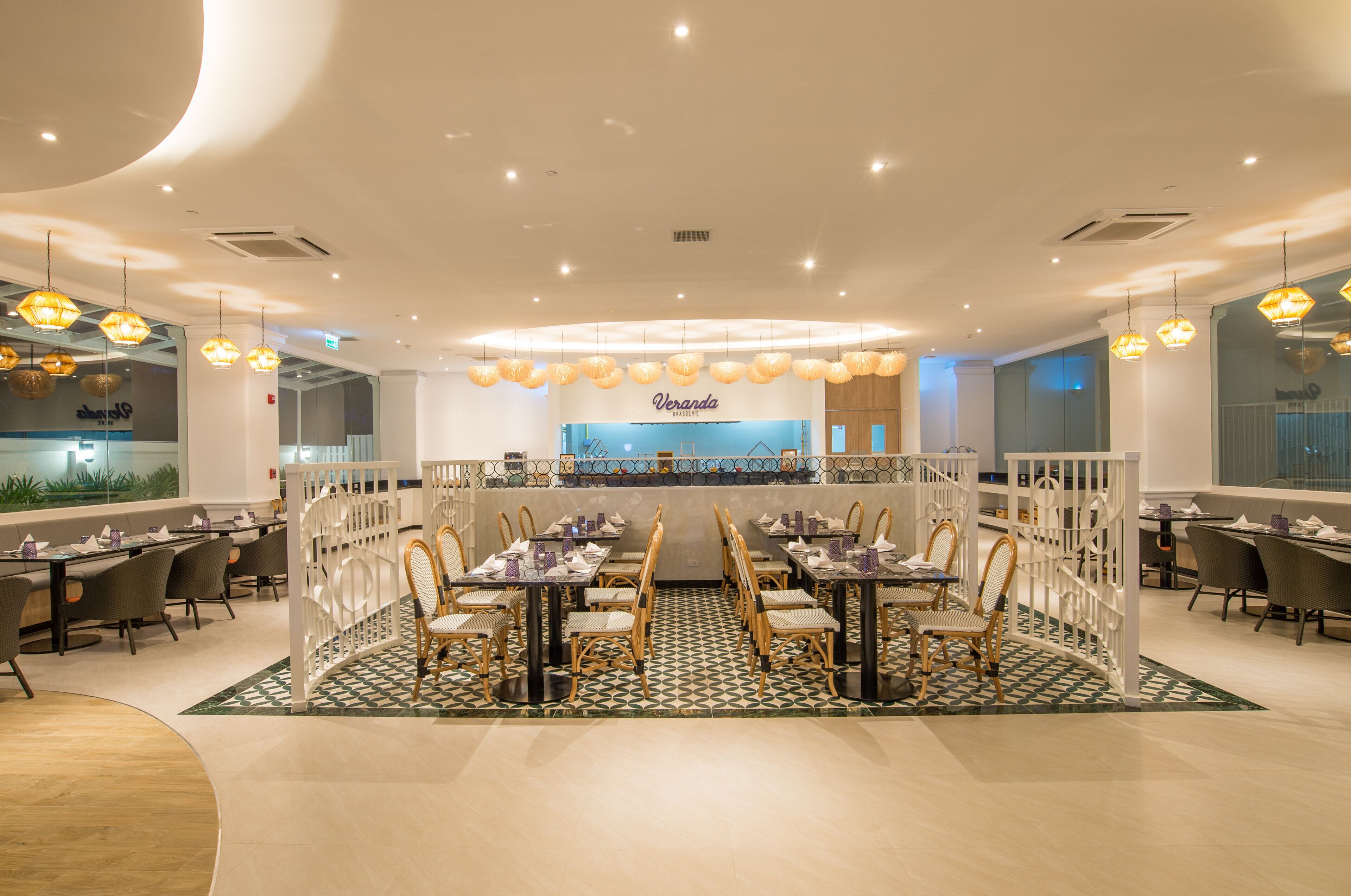 A spacious dining area with multiple tables and chairs, a central Veranda sign, and a patterned floor.