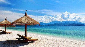 Ein Strand mit Reetsonnenstühlen und Holzliegestühlen.