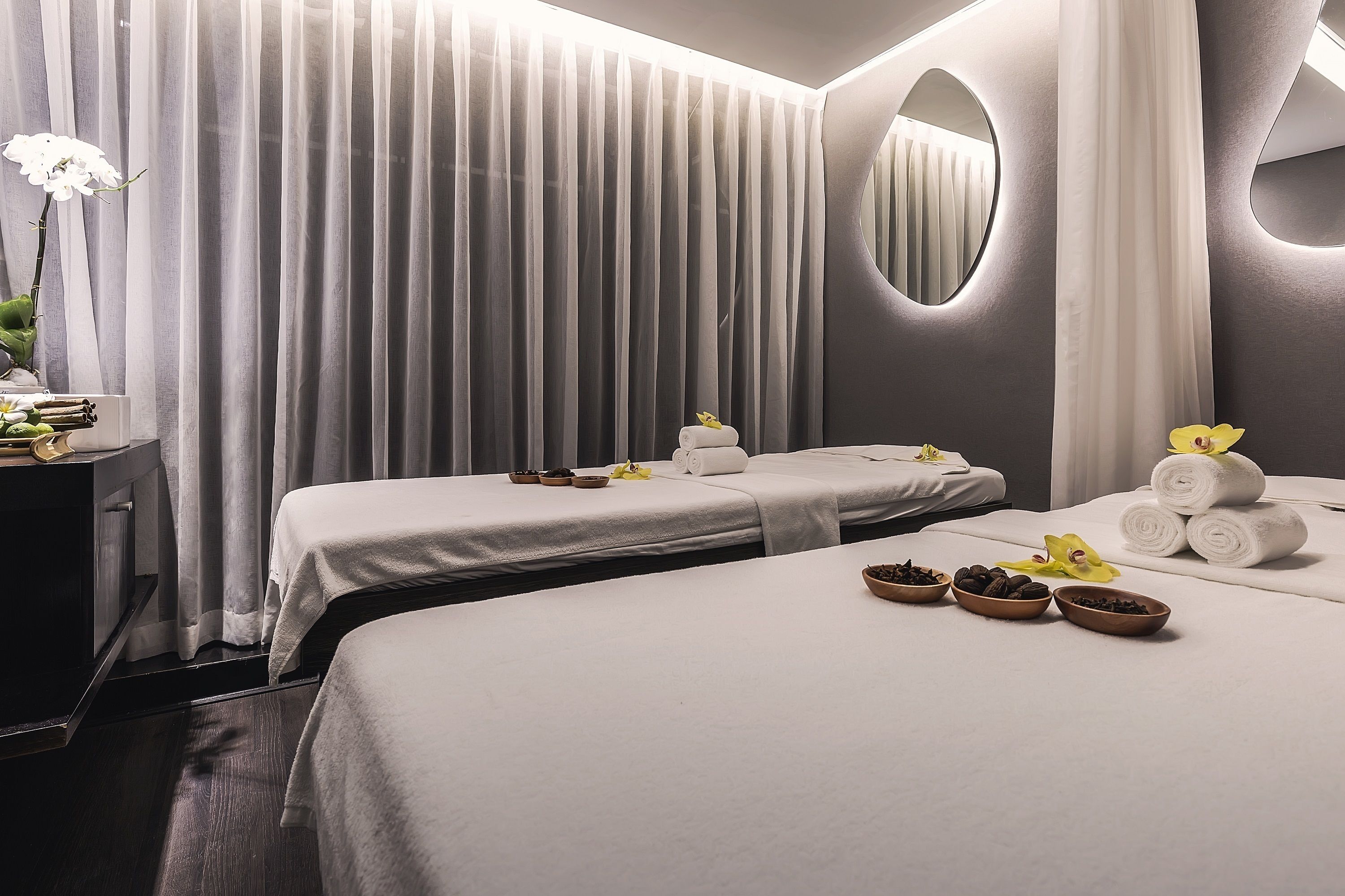 A hotel room with two beds, a mirror, and a curtain.