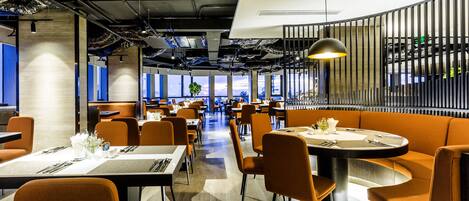 A modern restaurant with high ceilings, exposed ductwork, and a mix of seating including tables and booths.