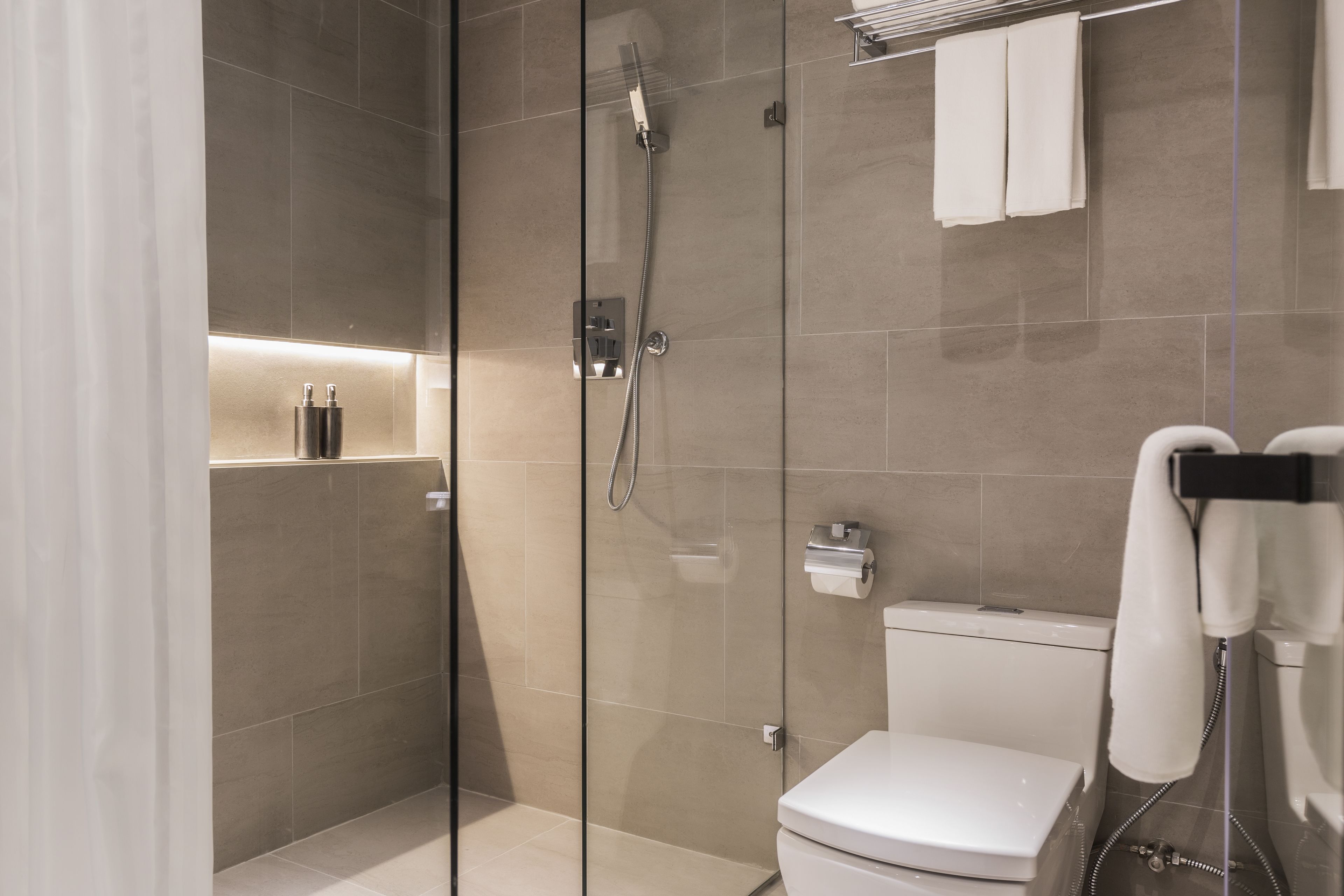 Une salle de bain moderne avec une douche à parois de verre, des toilettes et un porte-serviettes.