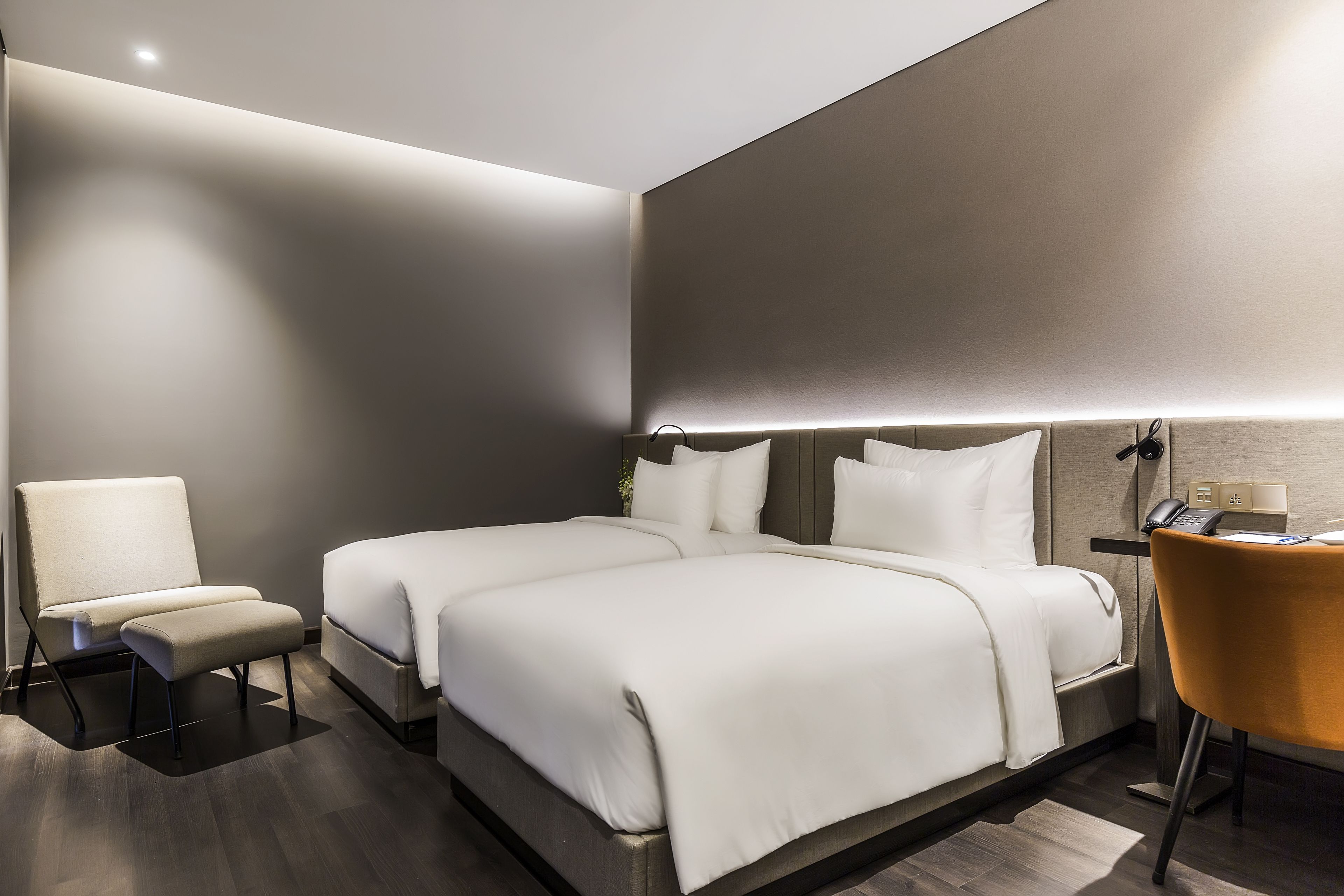 A modern hotel room with a large bed, a chair, and a desk.