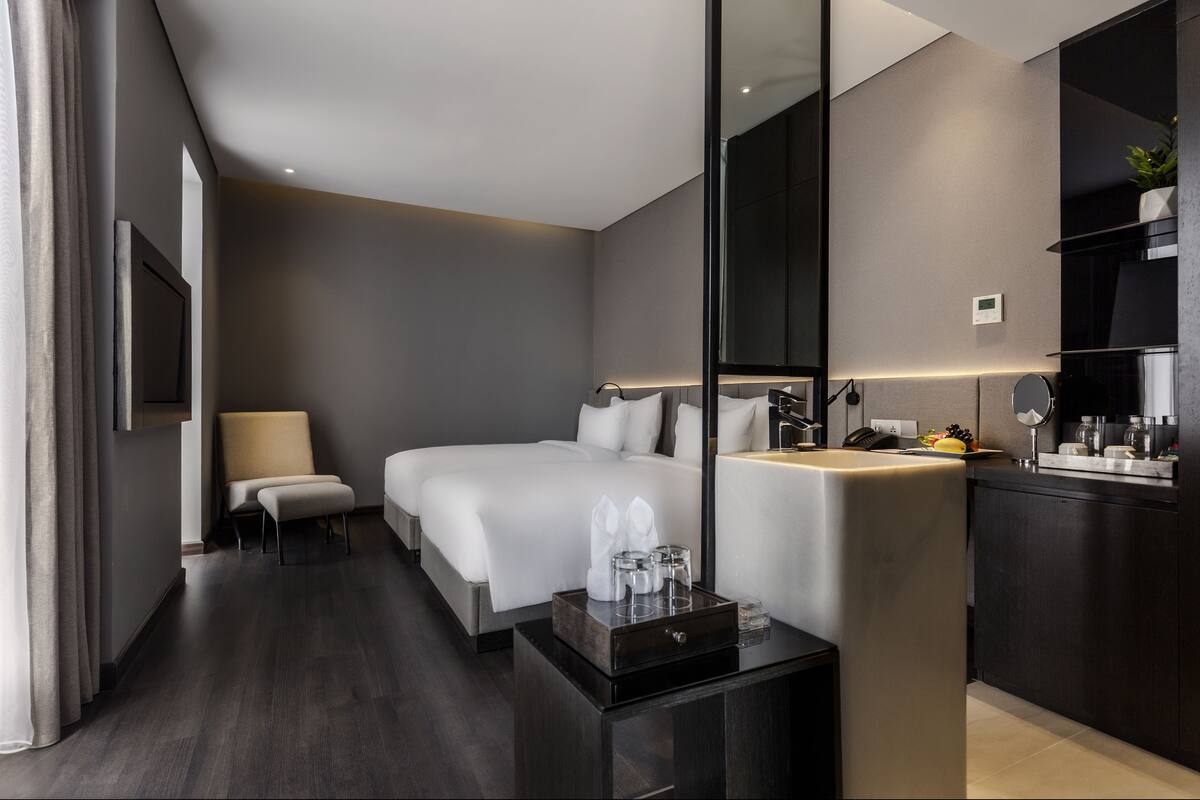 A modern hotel room with a large bed, bedside table, and a mirror.