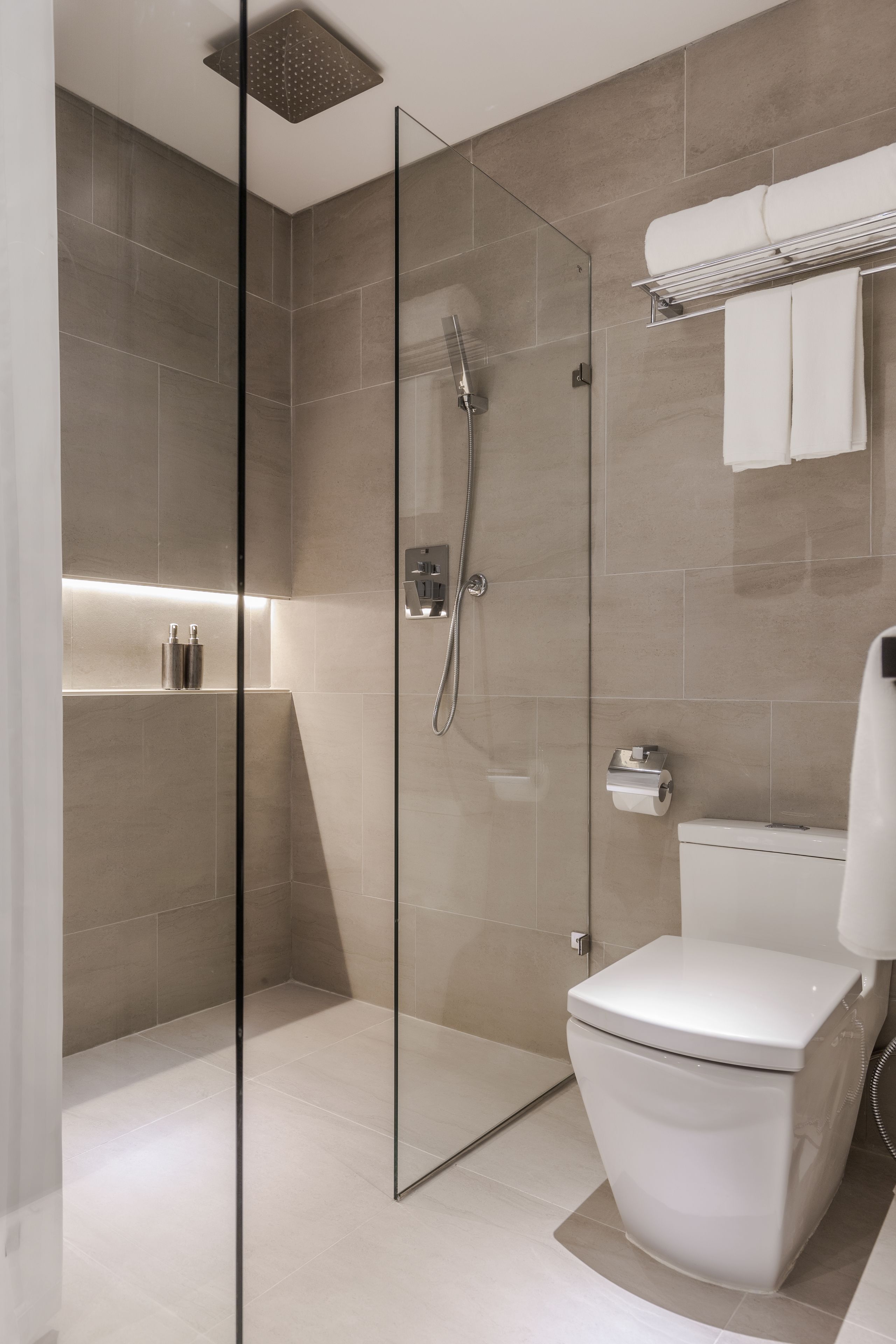 Un baño moderno con ducha de vidrio, inodoro blanco y toallero.