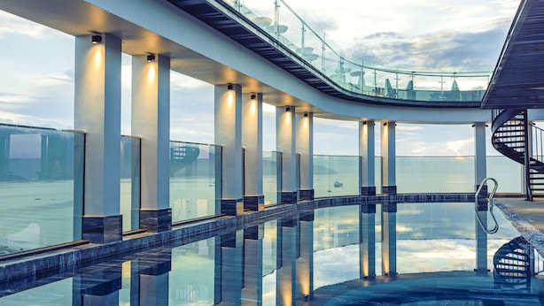 Eine moderne Architekturstruktur mit einem Pool mit Glasboden, der Himmel und umliegende Gebäude reflektiert.