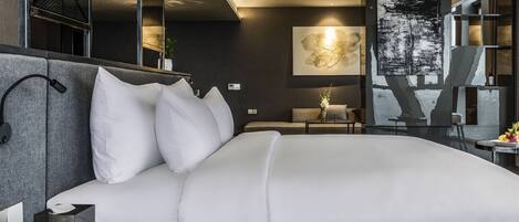 A modern hotel room with a large bed, a bedside table, a lamp, and a wall-mounted artwork.