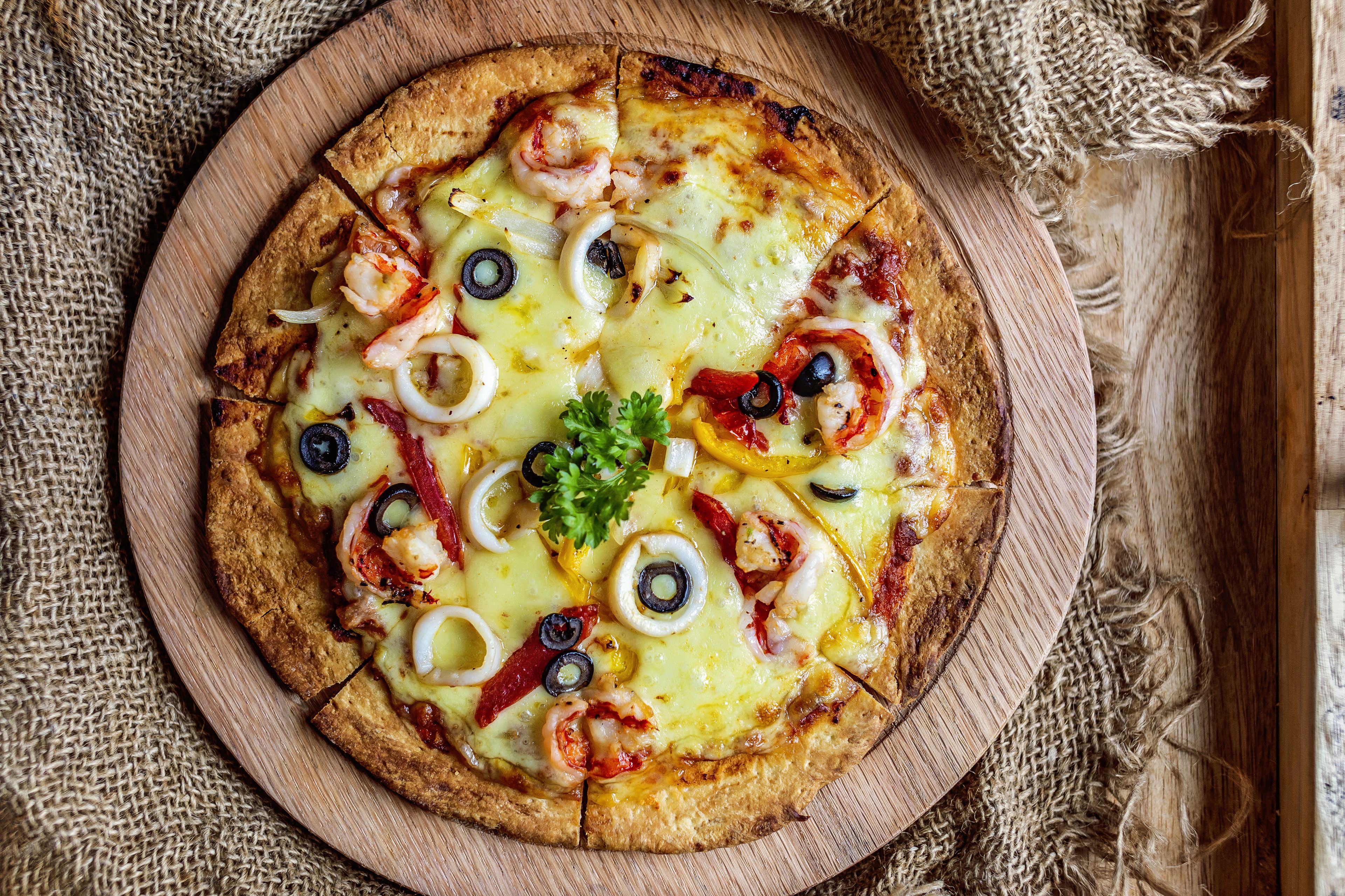 A pizza with various toppings on a wooden board.