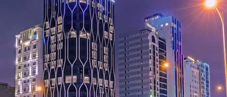 Un hotel con un diseño moderno característico, que presenta una fachada curva y señalización iluminada.