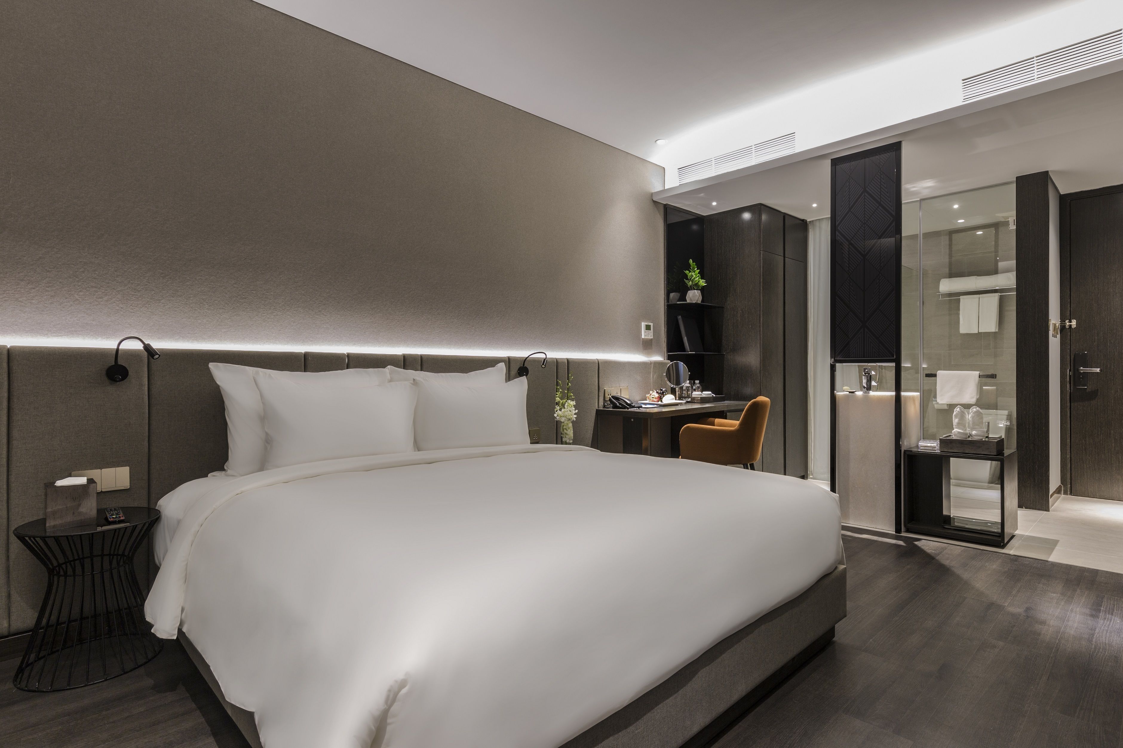 A modern hotel room with a large bed, a desk, and a walk-in closet.