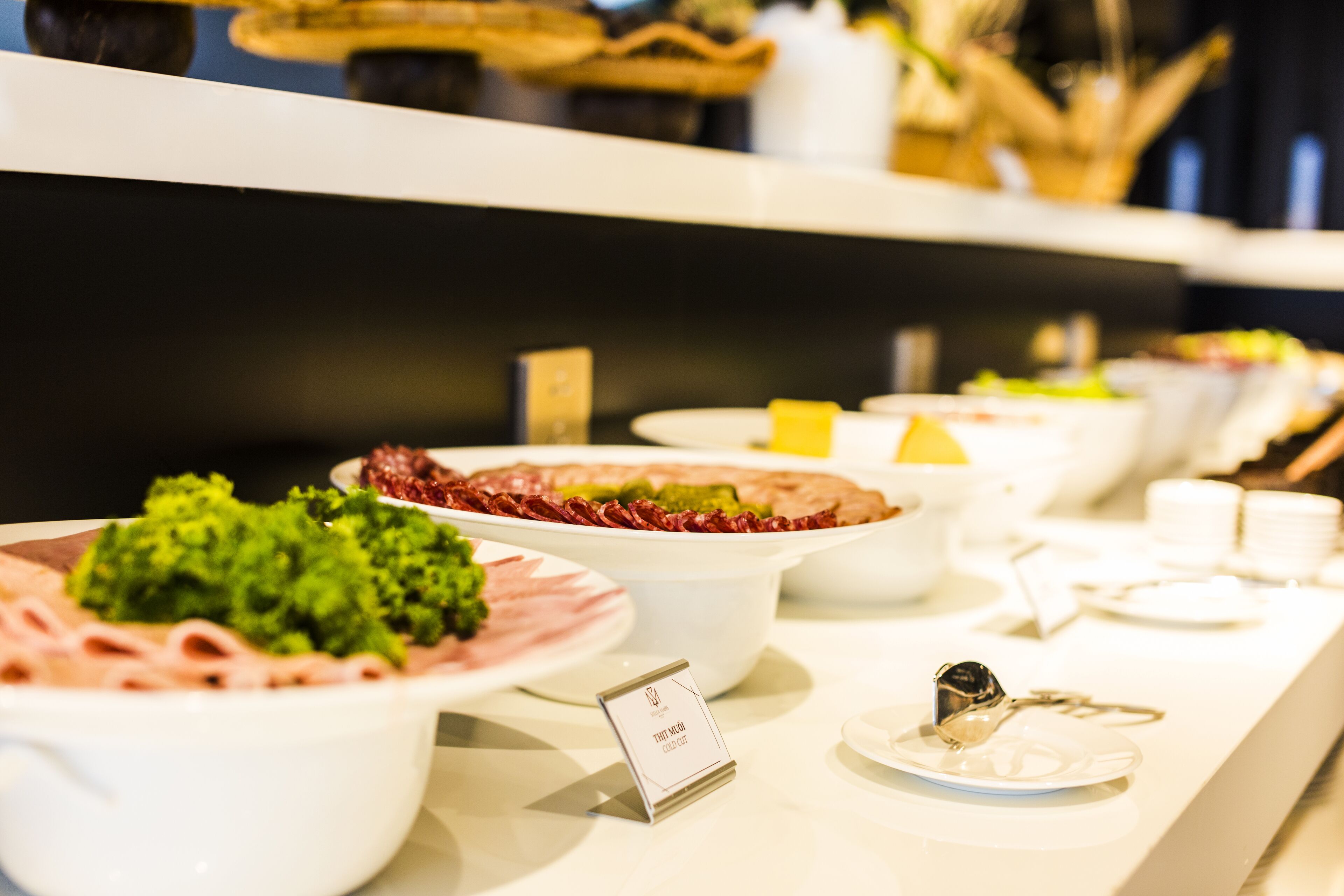 A buffet with various dishes including a green vegetable dish, a red meat dish, and a dessert.