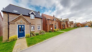 A row of brick houses with a clear driveway, a blue door, and a well-maintained lawn. - Sandy Shores - a cottage that sleeps 4 guests in 2 bedrooms (Filey)