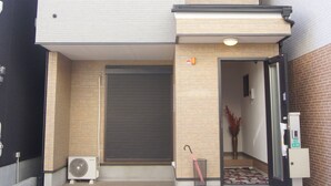 Un bâtiment à deux étages, doté d’un toit plat, d’une entrée couverte et d’un petit espace extérieur agrémenté d’un ventilateur et d’un parasol.