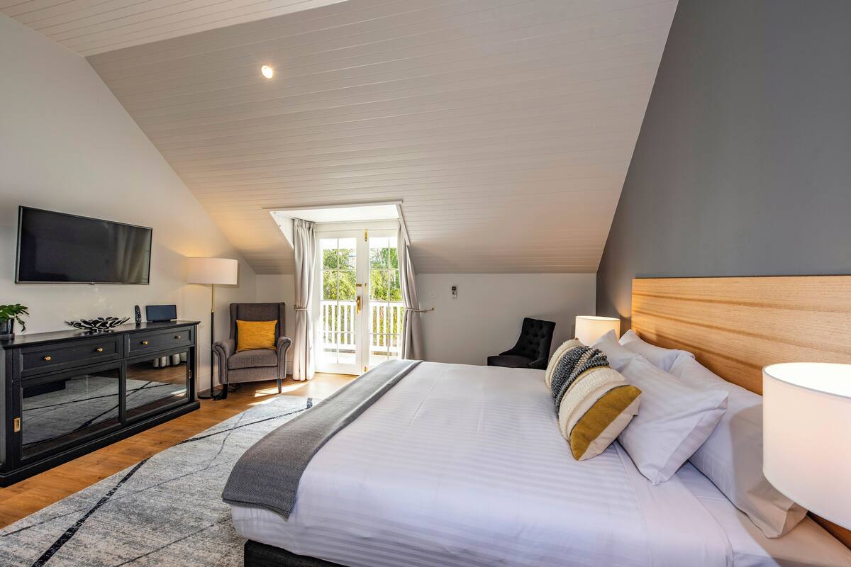 A bedroom with a large bed, a TV, a desk, and a chair.