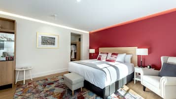 A modern bedroom with a large bed, a nightstand, a chair, a small table, and a wardrobe.