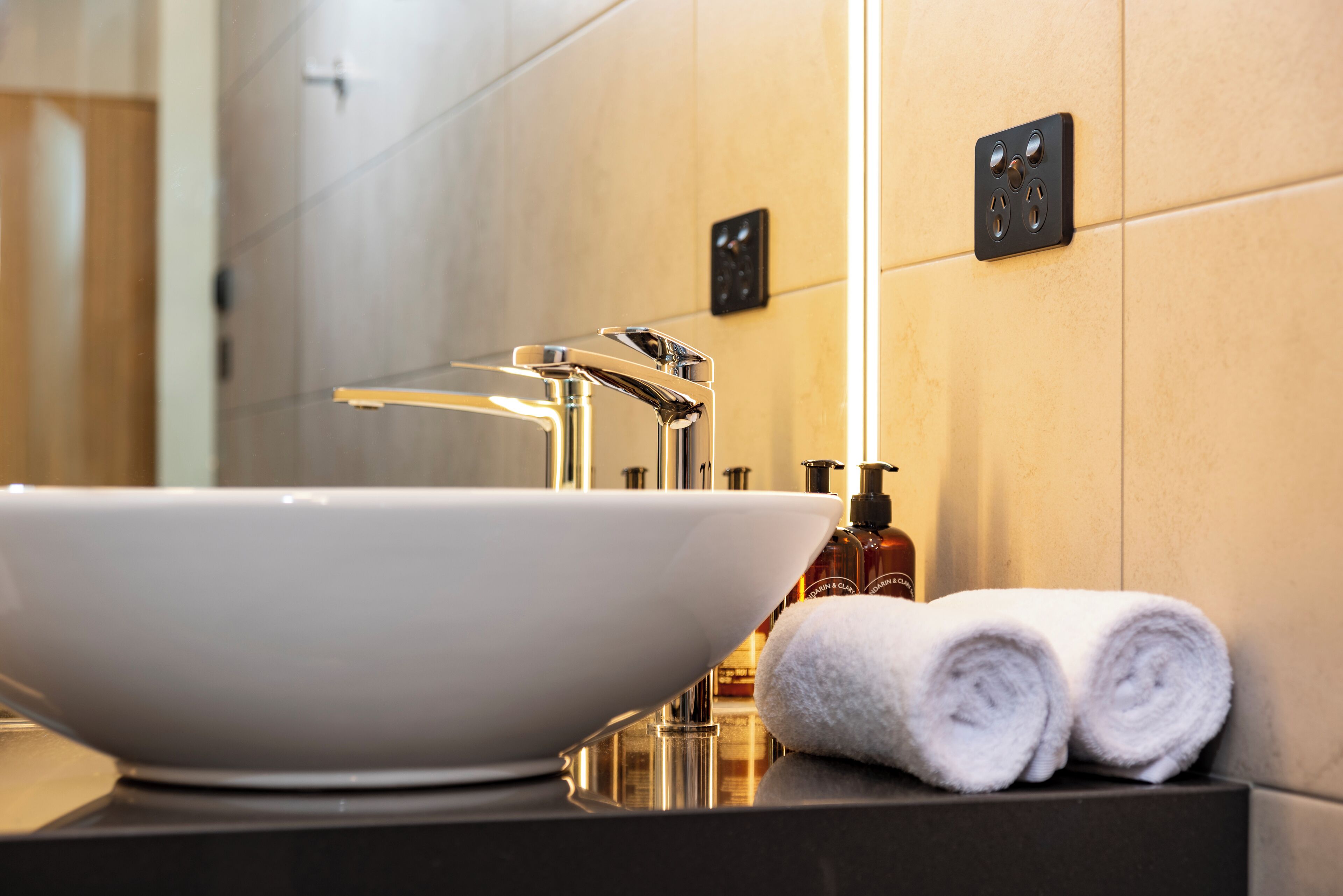 Un baño moderno con un lavabo blanco grande, un espejo y un perchero para toallas.
