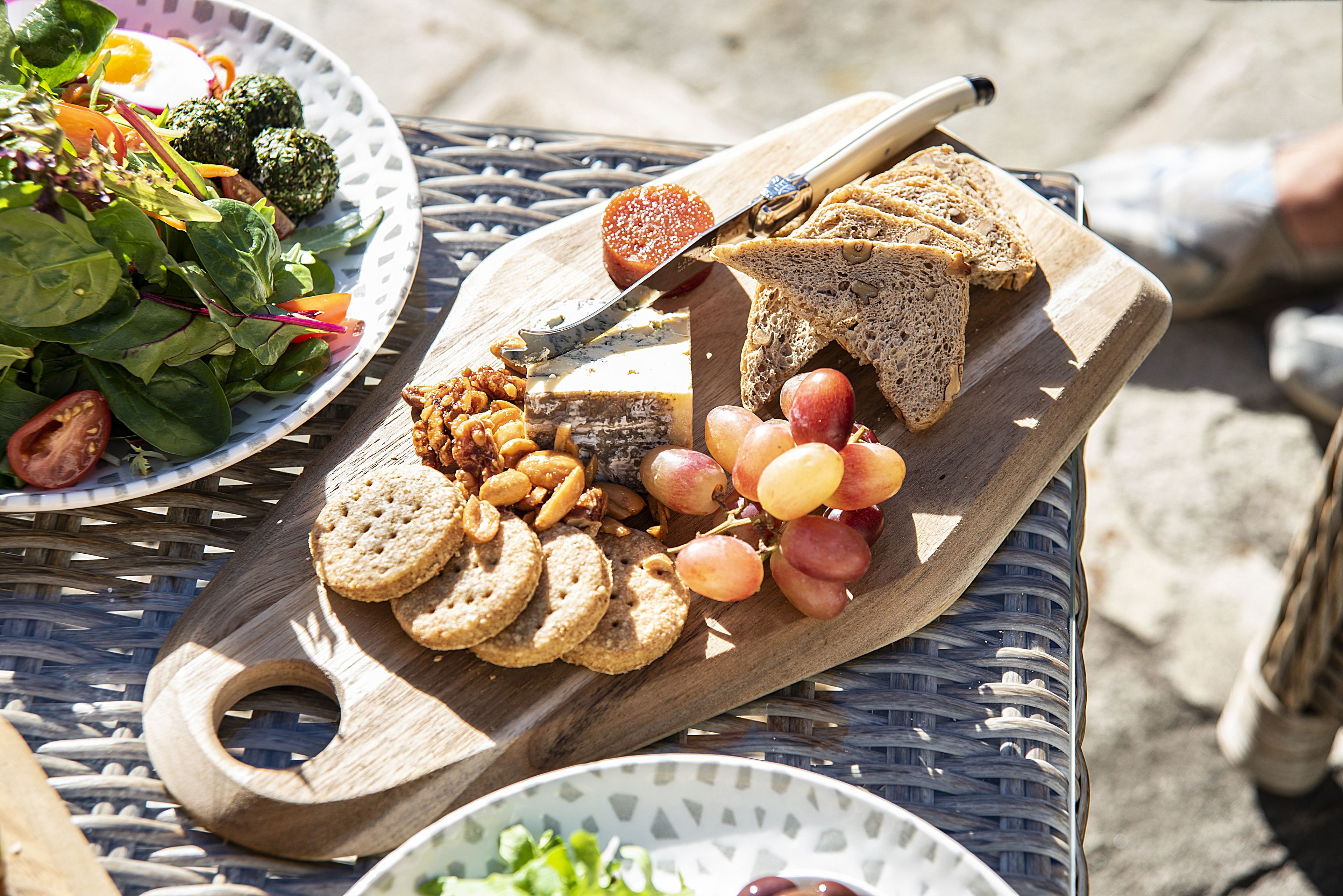 Ein Holzboden mit Brot, Trauben, Nüssen und Crackern auf einer Metalltischplatte.