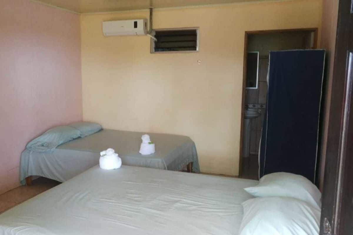 Ein Zimmer mit zwei Betten, einer kleinen Klimaanlage und einer Tür.