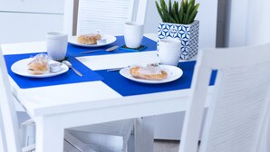 A dining area with white furniture, a blue tablecloth, and a white refrigerator.