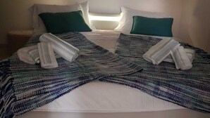 A neatly made bed with a striped blanket and two folded towels.