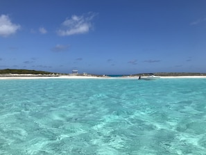 Enjoy a tranquil beach experience with access to turquoise waters and a nearby boat.