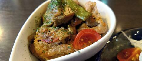 Un plato ovalado blanco con comida que incluye carne, verduras verdes y tomates.