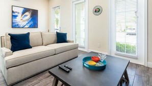 A living room with a beige sofa, a coffee table with a tray, and a painting on the wall.