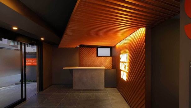 Un área de recepción moderna con techo inclinado, un mostrador de recepción y un letrero en la pared.