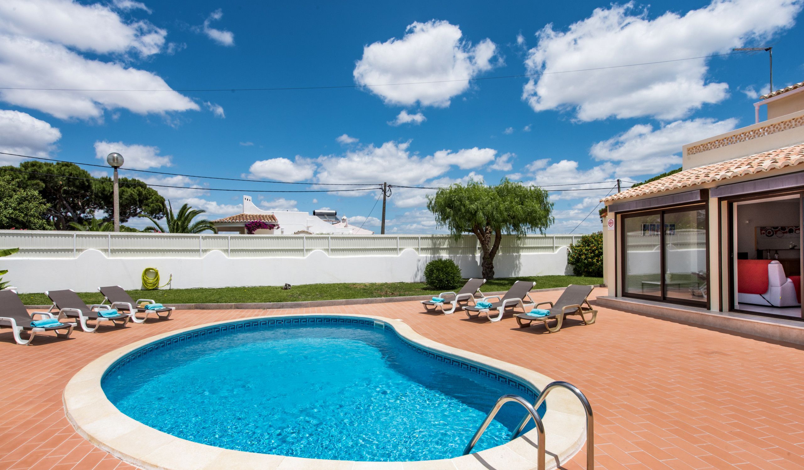 A swimming pool with lounge chairs and a clear view of the sky.