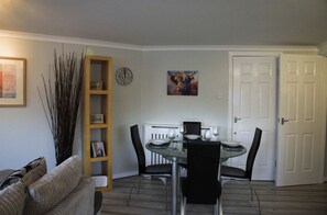 A dining area with a round table, black chairs, a white door, a bookshelf, and a painting on the wall. - The Stables: Fabulous stylish flat in Merchant City & Parking (Glasgow)