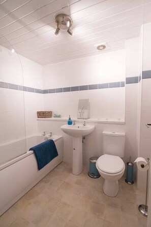 A bathroom with a bathtub, sink, toilet, and trash bins. - The Stables: Fabulous stylish flat in Merchant City & Parking (Glasgow)