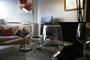 Ein Wohnzimmer mit Glastisch, einer Couch und einem Fernseher.