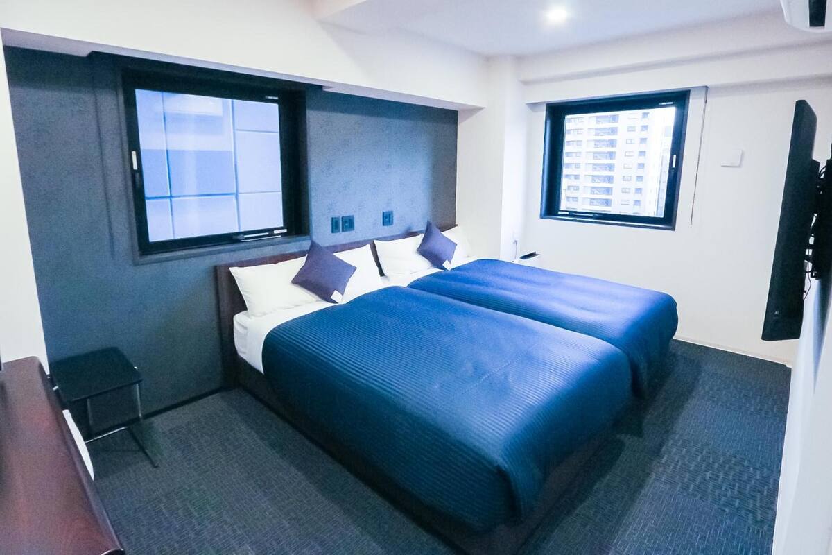 A hotel room with two beds, a desk, and a TV.