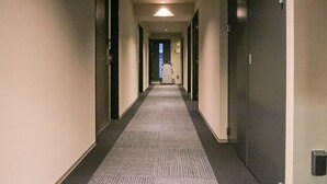 A hotel hallway with carpeted floors, doors on both sides, and a ceiling light. - Hotel Livemax Tokyoshintomicho (Tokyo)